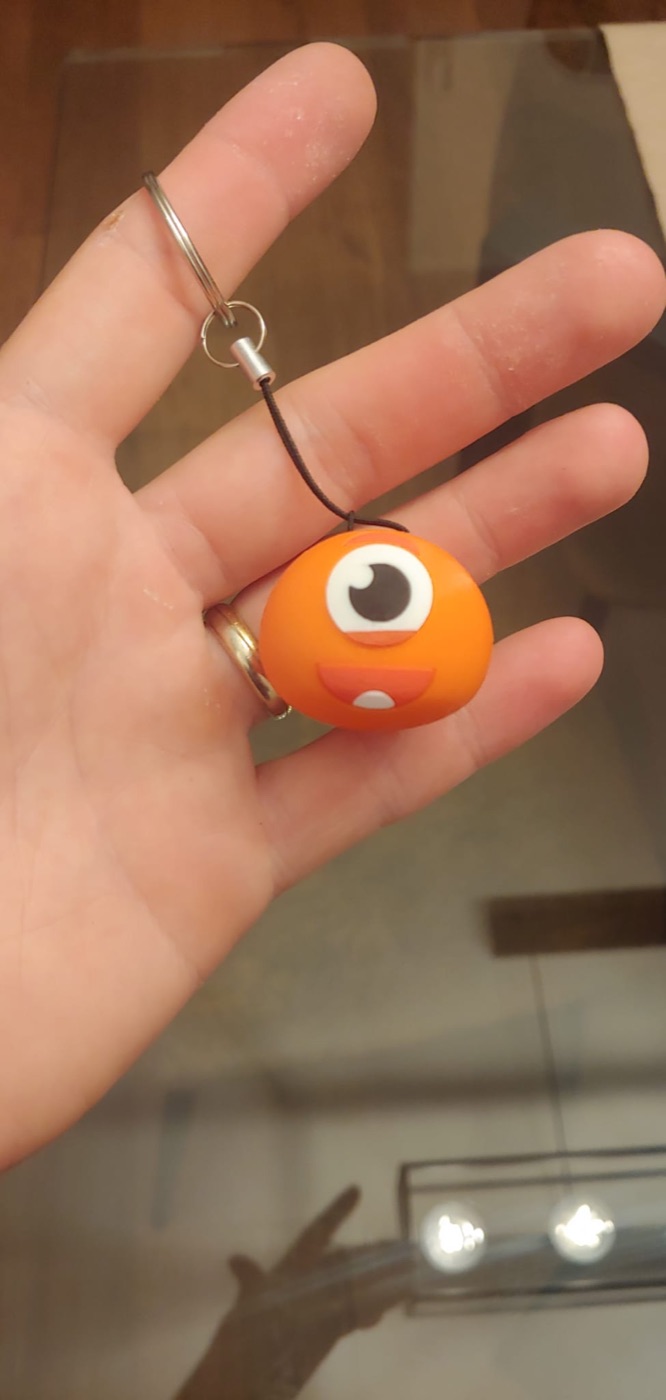 La mascotte MyNino in 3D, portachiavi arancione con un occhio e un sorriso